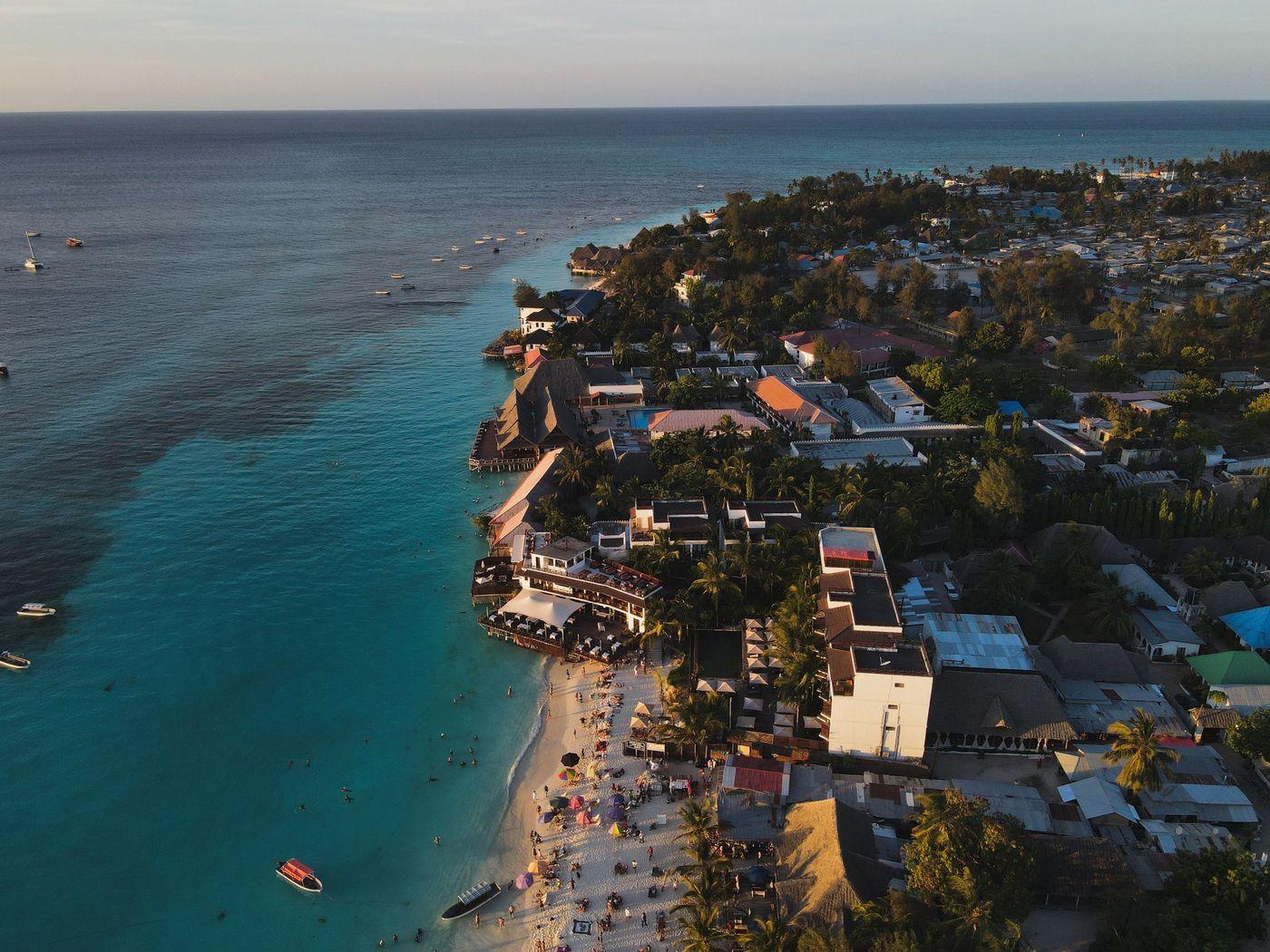 A pale sand beach curving into turquoise water at sunset